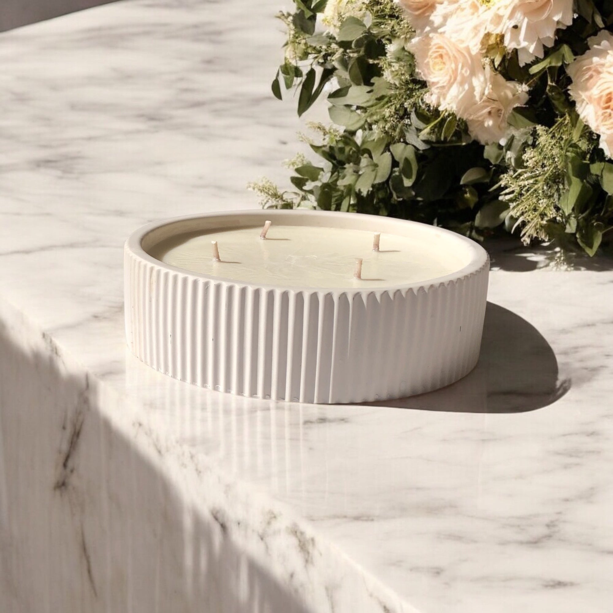 White Concrete Candle displayed on kitchen bench top with botanical flowers in background. Luxury Giant  Soy wax candle. Made in Australia
