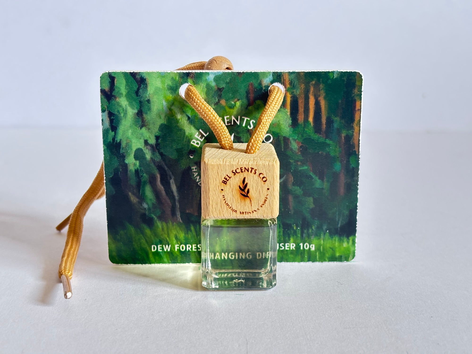 Tree Pine Scented hanging car diffuser bottle with wooden cap, suspended by string. Minimalist hanging diffuser for car interior. Hanging fragrance diffuser with Wood-topped diffuser adding a refreshing scent to a car interior. filled with essential oils for natural fragrance