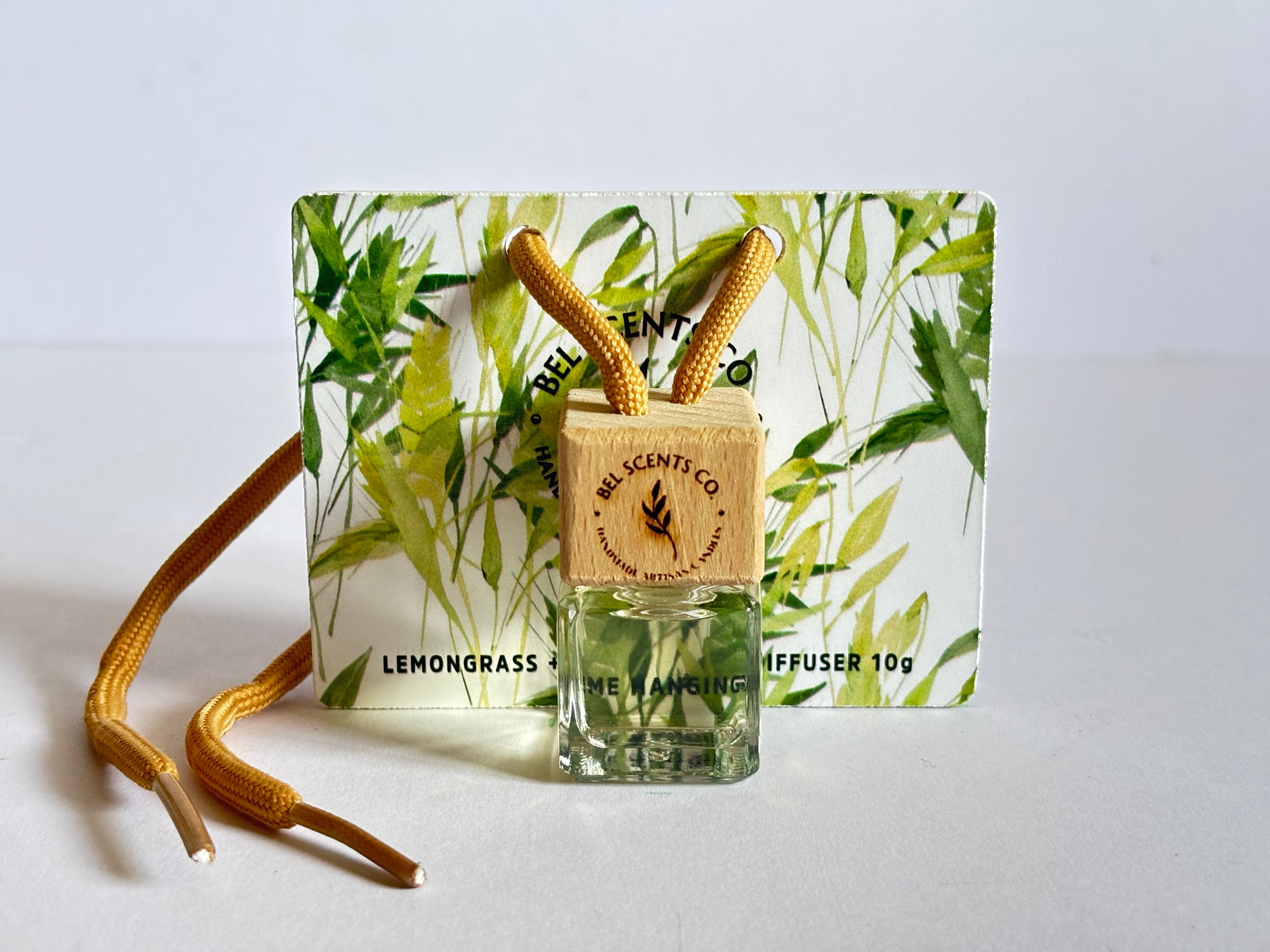 Fresh and Clean Lemongrass and Lime Scented hanging car diffuser bottle with wooden cap, suspended by string. Minimalist hanging diffuser for car interior. Hanging fragrance diffuser with Wood-topped diffuser adding a refreshing scent to a car interior. filled with essential oils for natural fragrance. popular scents for the car