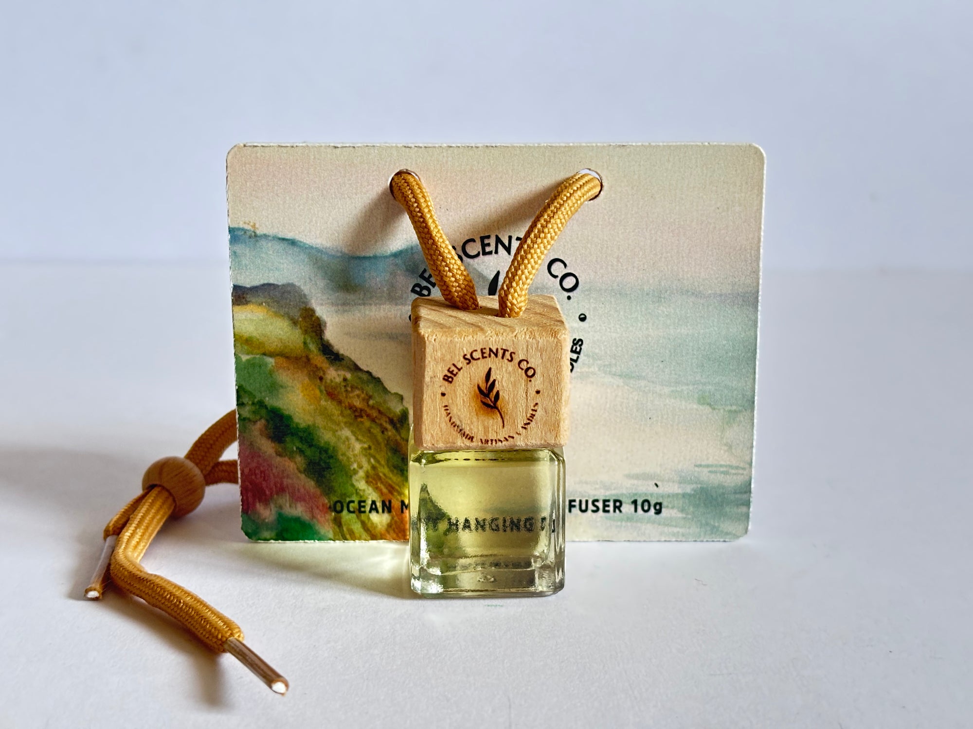 Scented hanging car diffuser bottle with wooden cap, suspended by string. Minimalist hanging diffuser for car interior. Hanging fragrance diffuser with Wood-topped diffuser adding a refreshing scent to a car interior. filled with essential oils for natural fragrance