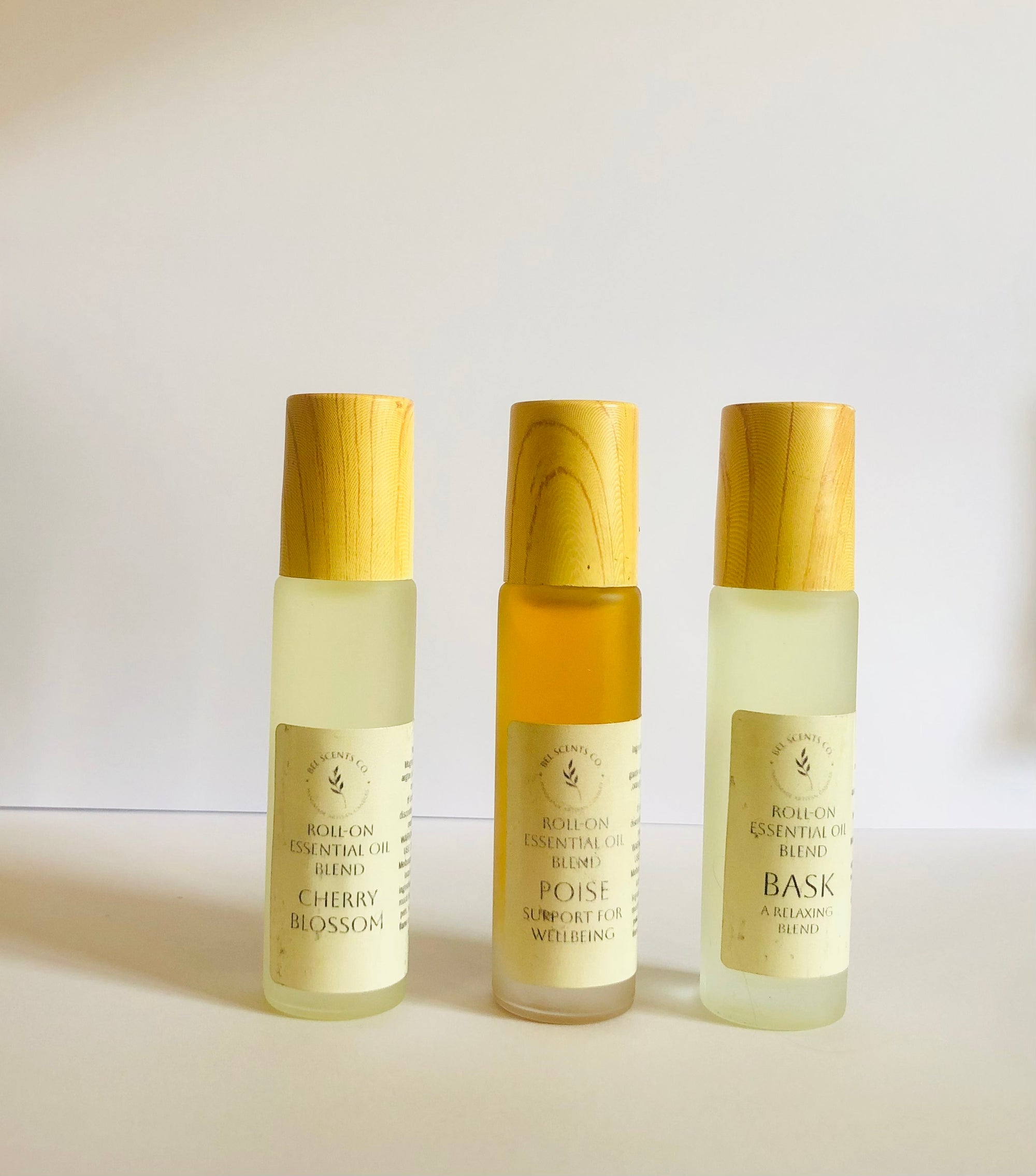 Three bottles of essential oil blends with wooden caps on a light background