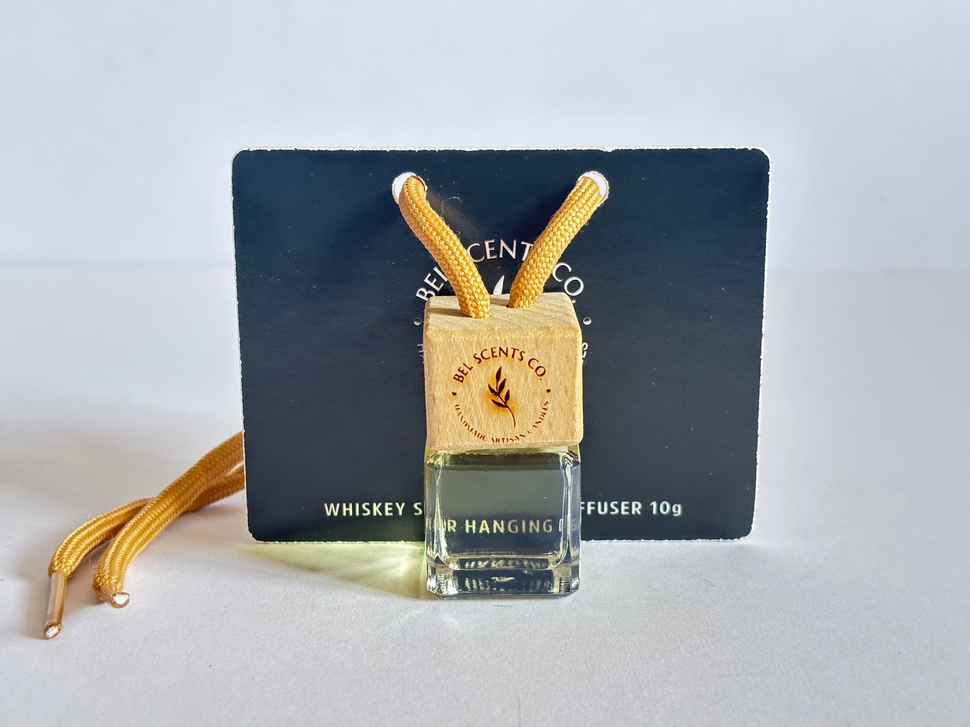 Whiskey Scented hanging car diffuser bottle with wooden cap, suspended by string. Minimalist hanging diffuser for car interior. Hanging fragrance diffuser with Wood-topped diffuser adding a refreshing scent to a car interior. filled with essential oils for natural fragrance. Mens Car Gift