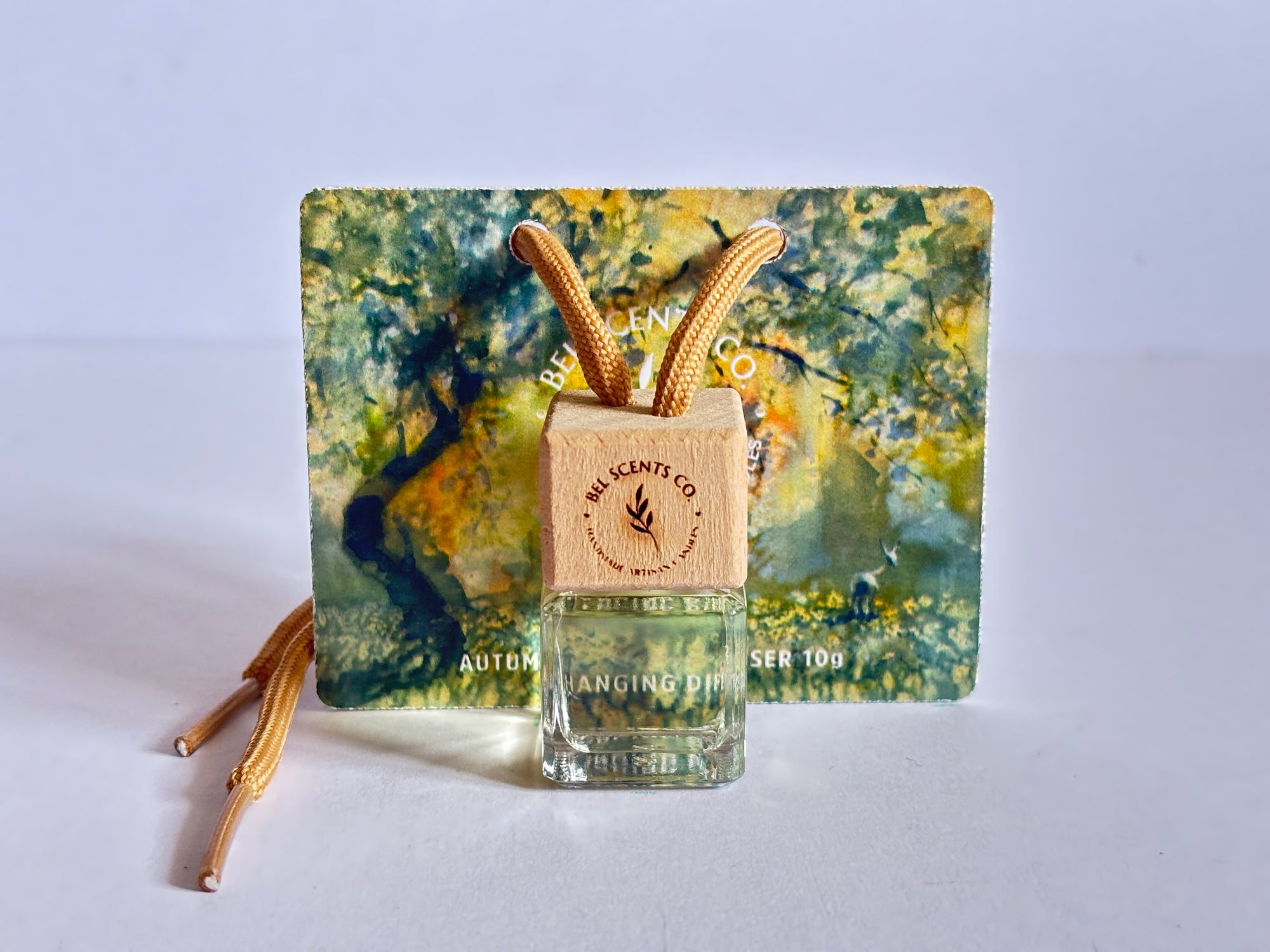 Autumn Scented hanging car diffuser bottle with wooden cap, suspended by string. Minimalist hanging diffuser for car interior. Hanging fragrance diffuser with Wood-topped diffuser adding a refreshing scent to a car interior. filled with essential oils for natural fragrance