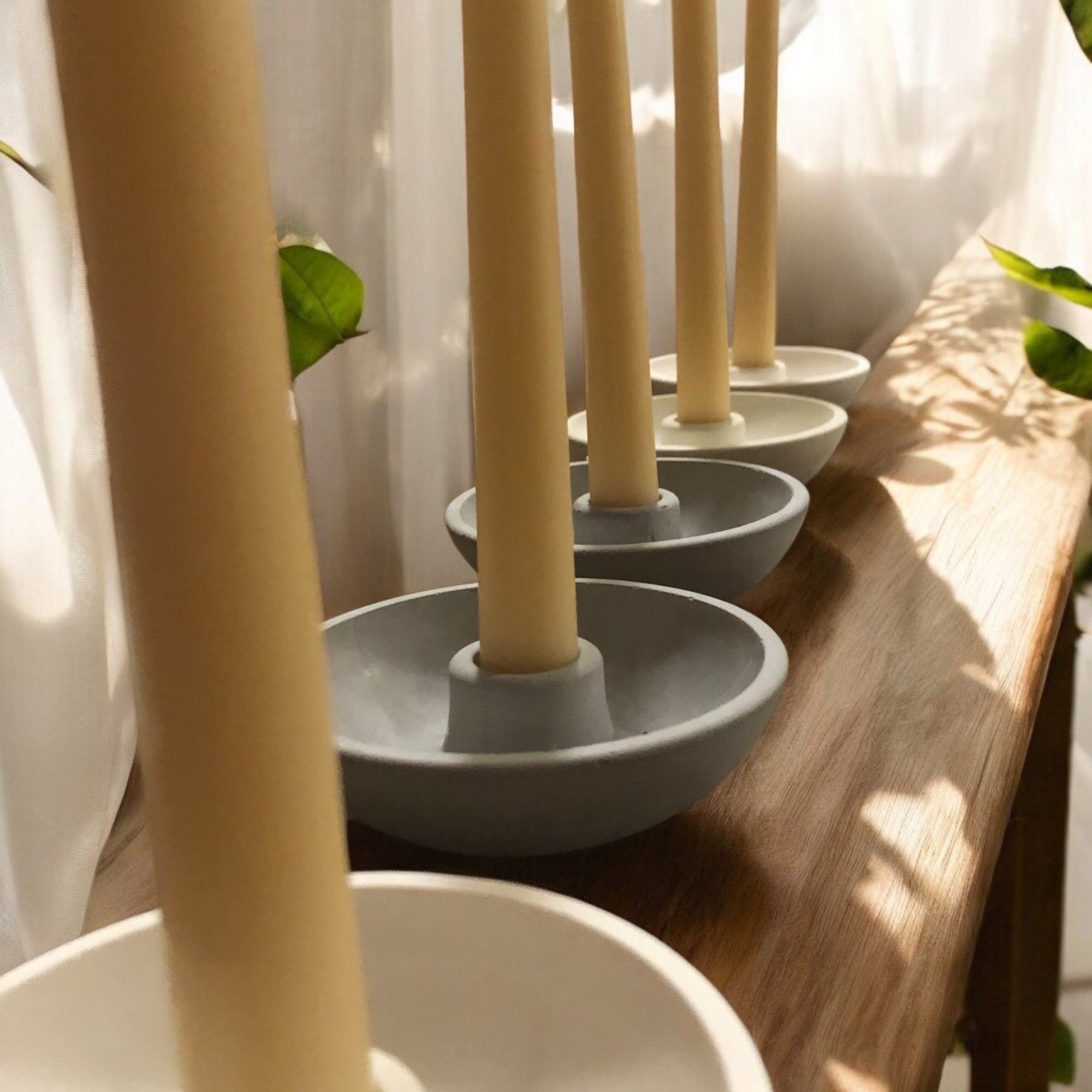 Concrete candle holders displayed with beeswax taper pillar candles. with concrete grey and white finish