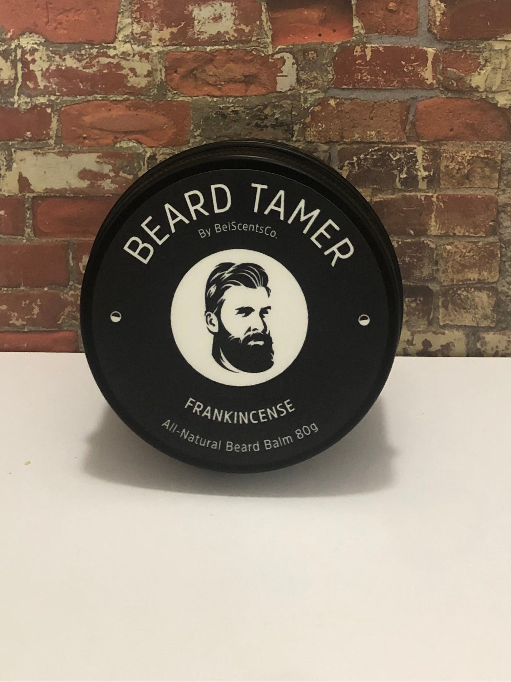 All-Natural Beard Balm for Men in Tin Container – Conditioning and Styling Balm with Essential Oils for Soft, Healthy Beard Care. Scented in Peru of Balsam Oil displayed on industrial brick wall setting