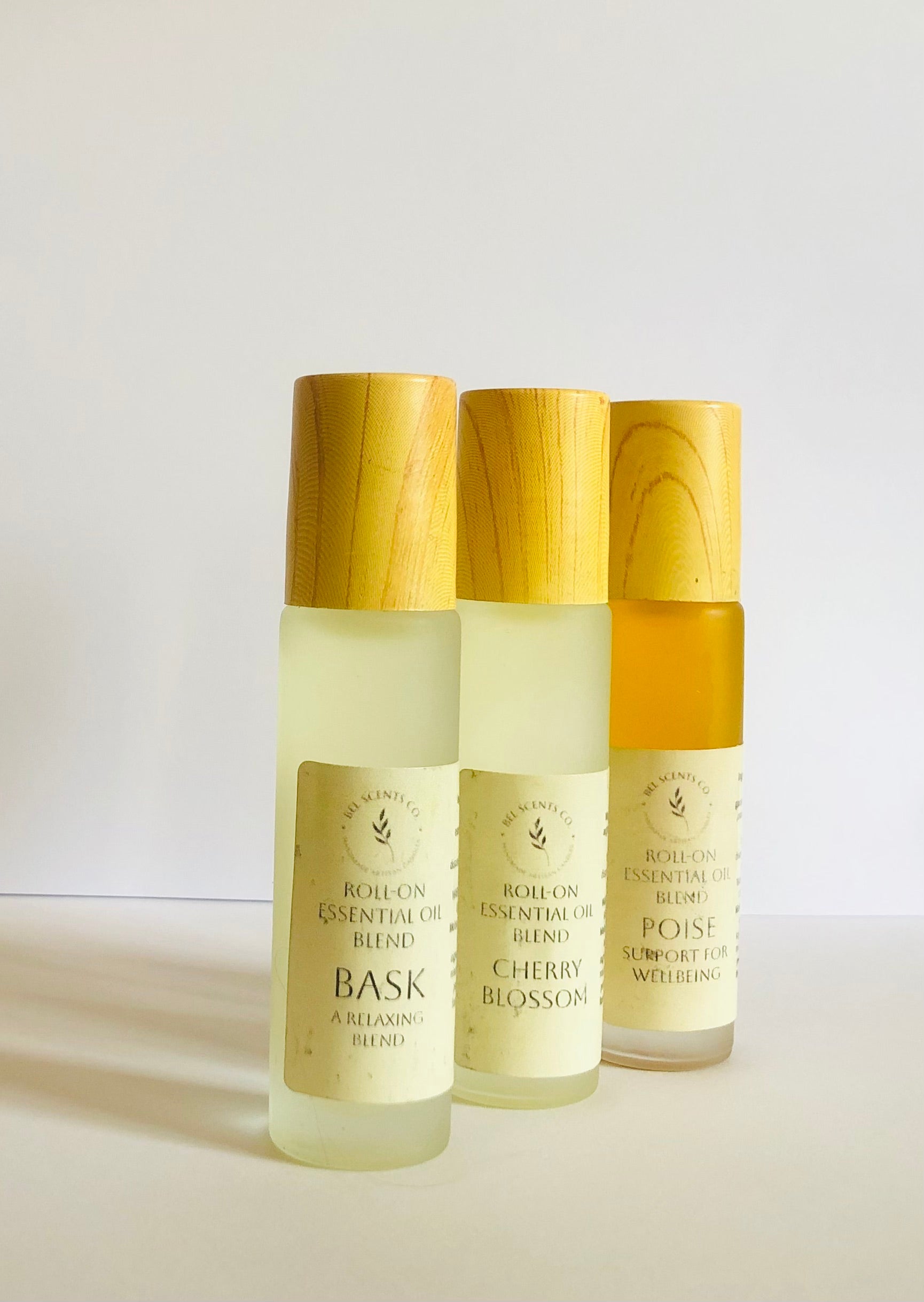 Three essential oil roller bottles with wooden caps on a light background